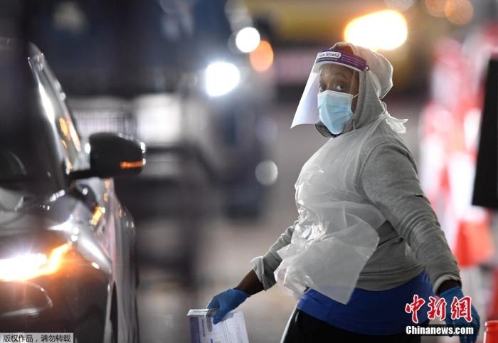 當(dāng)?shù)貢r(shí)間12月18日，英國政府公布的數(shù)據(jù)顯示，當(dāng)天英國新增奧密克戎毒株感染病例10059例。鑒于奧密克戎毒株感染病例激增，住院人數(shù)不斷上升，倫敦市長宣布倫敦進(jìn)入“重大事故”狀態(tài)。圖為倫敦的一個(gè)免下車檢測中心，一名醫(yī)務(wù)工作者正準(zhǔn)備對司機(jī)進(jìn)行核酸檢測。