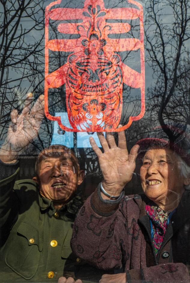 臘月里，霍州市師莊鄉(xiāng)馮南垣村村民師榮光(左)在災(zāi)后重建的新家里貼窗花。(霍州市委宣傳部供圖)