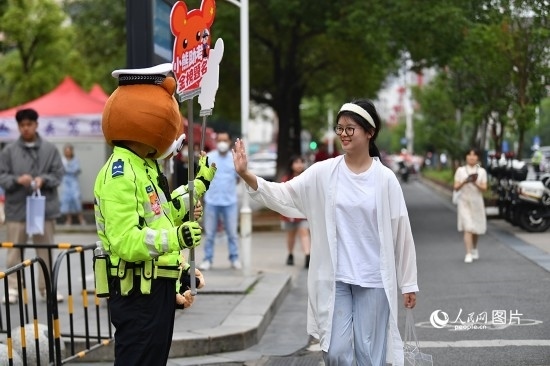 6月7日上午9時(shí)，隨著鈴聲的響起，2023年江西高考正式開(kāi)考，江西省的53.57萬(wàn)考生以縣（區(qū)）為單位隨機(jī)安排在全省256個(gè)考點(diǎn)、18968個(gè)考場(chǎng)參加高考。圖為“小熊交警”和考生擊掌鼓勵(lì)。 人民網(wǎng)記者 時(shí)雨攝