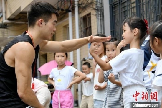 圖為大學(xué)生志愿者在組織孩子們參加體育健身活動。廖光福 攝