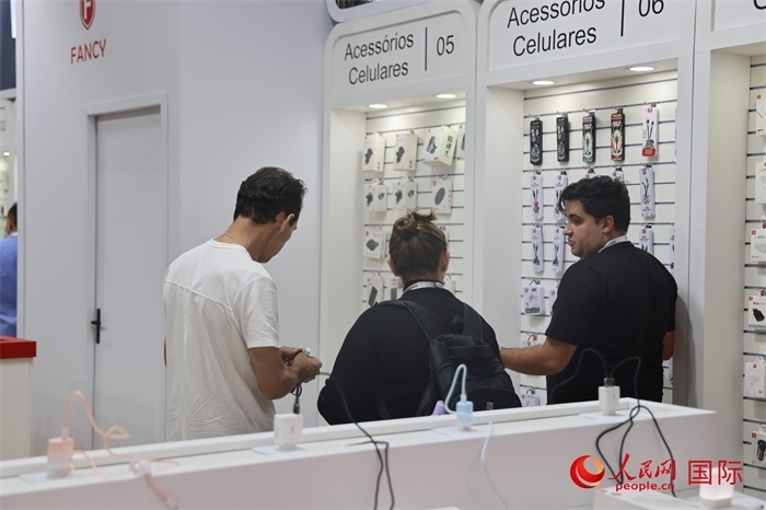 幾名參觀者在一個(gè)展臺(tái)前了解手機(jī)配件。（人民網(wǎng)記者 時(shí)元皓攝）