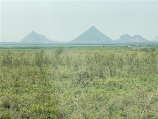 遠處礦方存放的矸石堆成山（中國之聲記者江曉晨 攝）