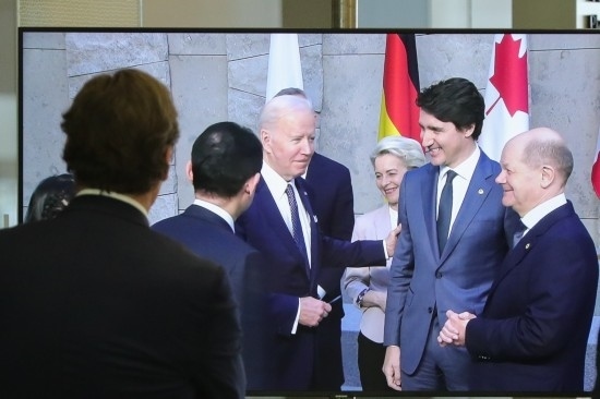 2022年3月24日，在比利時(shí)布魯塞爾的北約總部，一名男子觀看屏幕上美國總統(tǒng)拜登（右四）、歐盟委員會主席馮德萊恩（右三）、加拿大總理特魯多（右二）、德國總理朔爾茨（右一）出席七國集團(tuán)峰會合影儀式的畫面。新華社記者鄭煥松攝