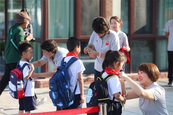 8月30日，雄安史家胡同小學學生體驗學校生活。老師為學生佩戴?；?。
