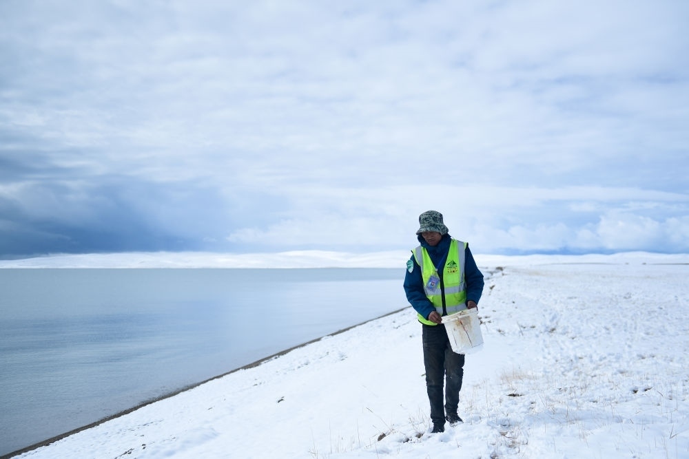 2021年10月20日，在青海省果洛藏族自治州瑪多縣扎陵湖鄉(xiāng)勒那村，三江源國(guó)家公園黃河源園區(qū)生態(tài)管護(hù)員在扎陵湖邊撿拾垃圾。新華社記者 張龍 攝