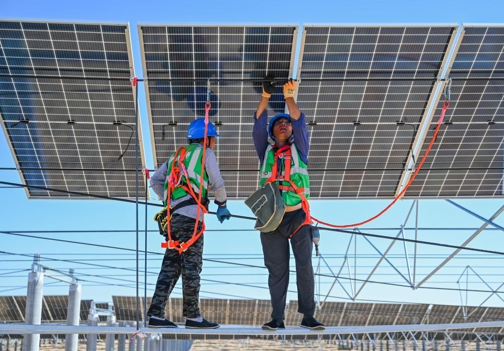 2023年7月22日，工人在位于內(nèi)蒙古杭錦旗庫(kù)布其沙漠億利生態(tài)示范區(qū)的蒙西基地庫(kù)布其200萬(wàn)千瓦光伏治沙項(xiàng)目工地安裝光伏板。新華社記者 劉磊 攝