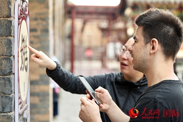 選手安德烈（俄羅斯）在老師指導(dǎo)下學(xué)習(xí)墻壁上張貼的生僻字。人民網(wǎng) 盧鵬宇攝