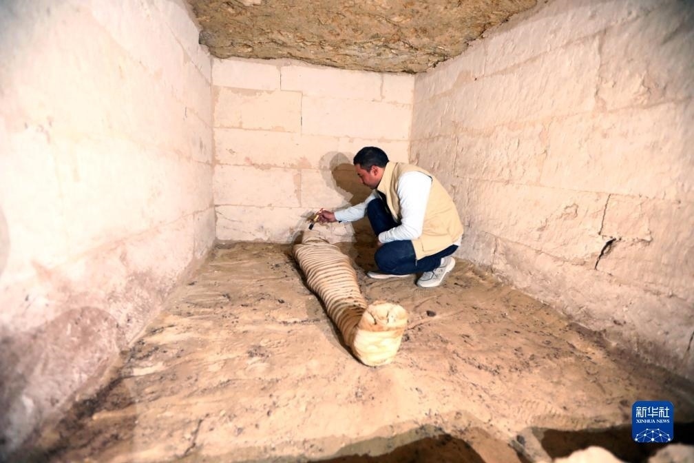 10月15日，在埃及明亞省考古現(xiàn)場，考古人員清理一座石鑿墓中的木乃伊。新華社發(fā)（艾哈邁德·戈馬攝）