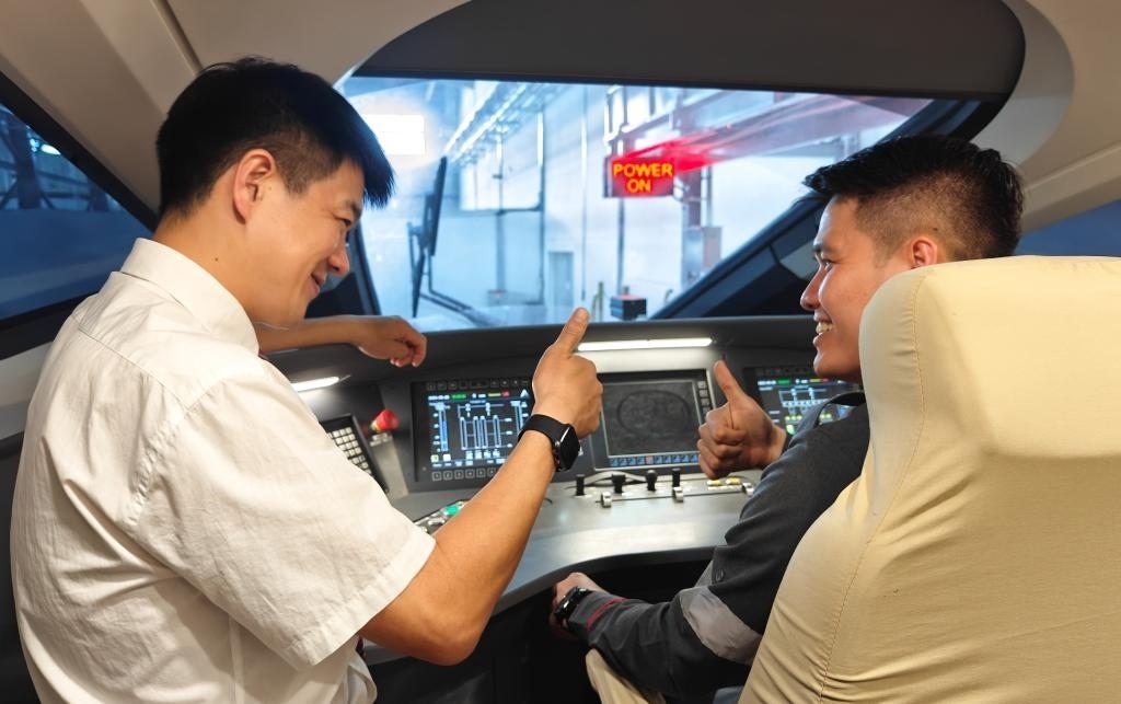 8月25日，在印度尼西亞萬隆的雅萬高鐵德卡魯爾動車所內(nèi)，中國師傅穆振（左）在向印尼火車司機塞蒂亞萬講解動車組出庫前的上電作業(yè)。