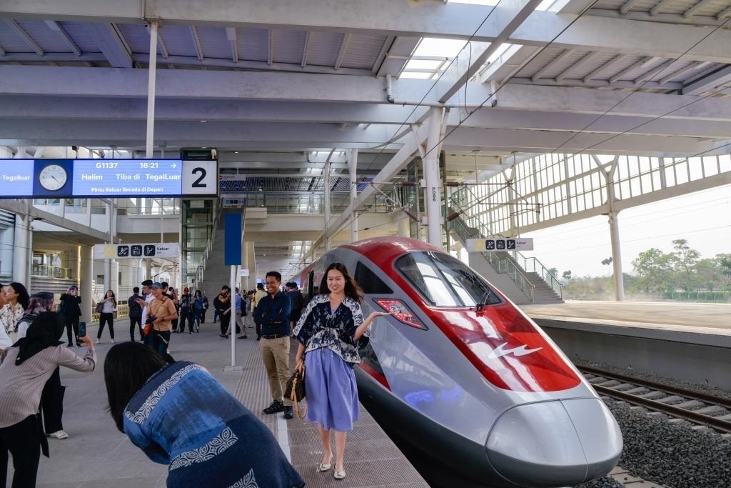 10月17日，在印度尼西亞萬隆德卡魯爾站，乘客在站臺上和雅萬高鐵高速動車組列車合影。