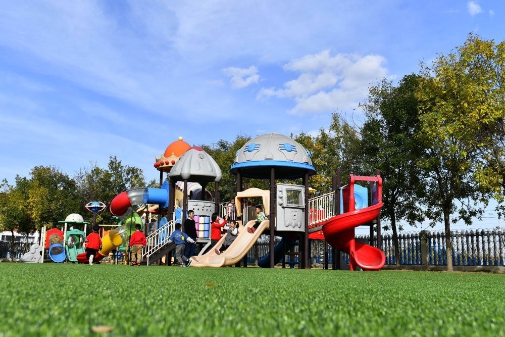 在山東省東營市墾利區(qū)楊廟社區(qū)幼兒園，孩子們?cè)诶蠋煹膸ьI(lǐng)下進(jìn)行戶外活動(dòng)（2021年10月19日攝）。新華社記者 郭緒雷 攝