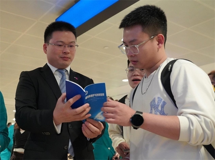 工作人員（左一）在發(fā)放《中國(guó)領(lǐng)事保護(hù)與協(xié)助指南》。 中國(guó)駐迪拜總領(lǐng)事館供圖