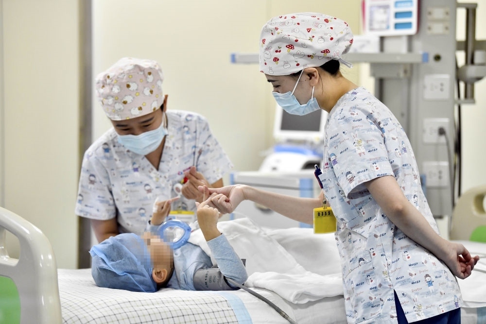 在山東省棗莊市婦幼保健院兒童ICU病房，醫(yī)護人員為完成靶向治療藥物諾西那生鈉的4歲脊髓性肌萎縮癥患兒加油鼓勁（2022年1月1日攝）。諾西那生鈉注射液是我國首個獲批治療脊髓性肌萎縮癥的進口藥物，2019年進入中國市場時，每針價格近70萬元。在2021年國家醫(yī)保目錄藥品談判中，以3.3萬元每針的價格進入新版醫(yī)保藥品目錄。新華社記者 郭緒雷 攝