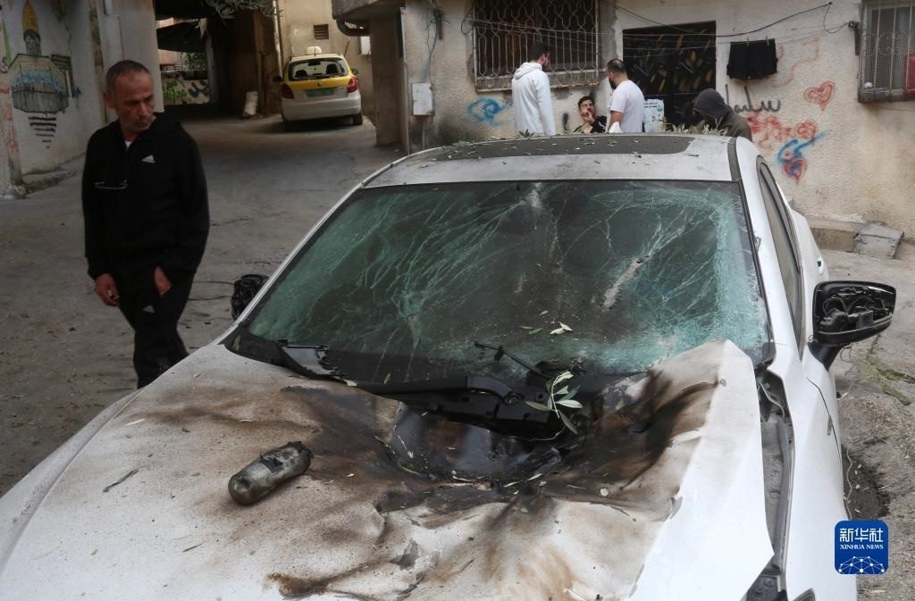12月17日，在約旦河西岸城市圖勒凱爾姆附近的一處難民營，人們查看在沖突中損毀的車輛。新華社發(fā)（尼達(dá)爾·艾仕塔耶?dāng)z）