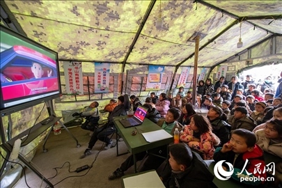 12月22日，在積石山縣大河家鎮(zhèn)大河村安置點，陸軍76集團軍某旅搭建的“臨時學校”內(nèi)，小朋友正在看動畫片。人民網(wǎng)記者 翁奇羽攝