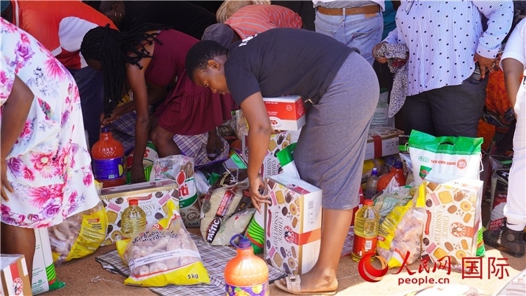 當(dāng)?shù)厣鐓^(qū)家庭領(lǐng)取物資。人民網(wǎng) 張茜攝