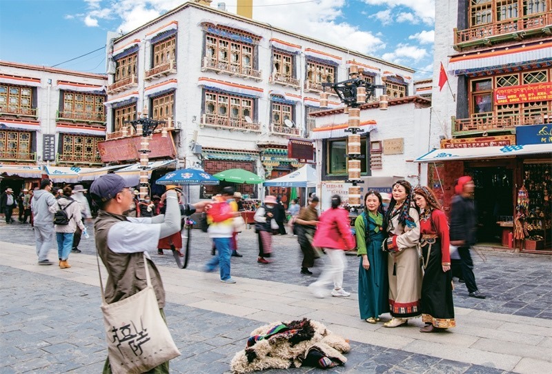 千年八廓街，見(jiàn)證民族團(tuán)結(jié)。2021年7月，習(xí)近平總書(shū)記來(lái)到位于西藏拉薩老城區(qū)的八廓街，感慨地說(shuō)：“千年八廓街，是我們各民族建起來(lái)的八廓街。各民族文化在這里交流交往交融，我們中華民族的大家庭在這里其樂(lè)融融。”圖為2023年6月13日，游客身著藏裝在八廓街拍照留念。 新華社記者 姜帆/攝