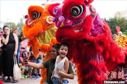 圖為舞獅表演吸引民眾合影。張興龍攝