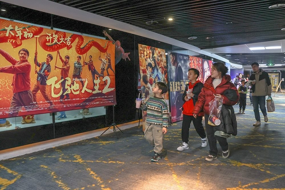 △ 2024年2月16日，在江西贛州一家電影院，觀眾從春節(jié)檔電影的宣傳展板前走過(guò)。