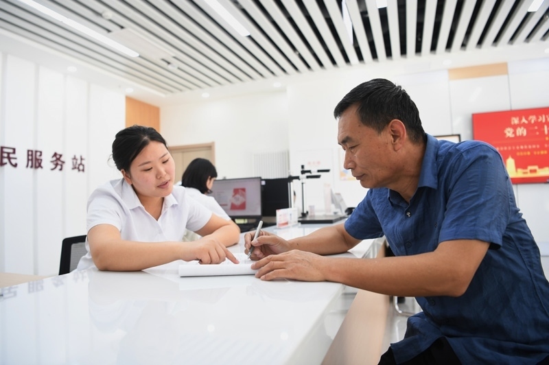 2023年5月23日，河北雄安新區(qū)容東片區(qū)南文營(yíng)社區(qū)居民（右）在社區(qū)便民服務(wù)站辦理業(yè)務(wù)。