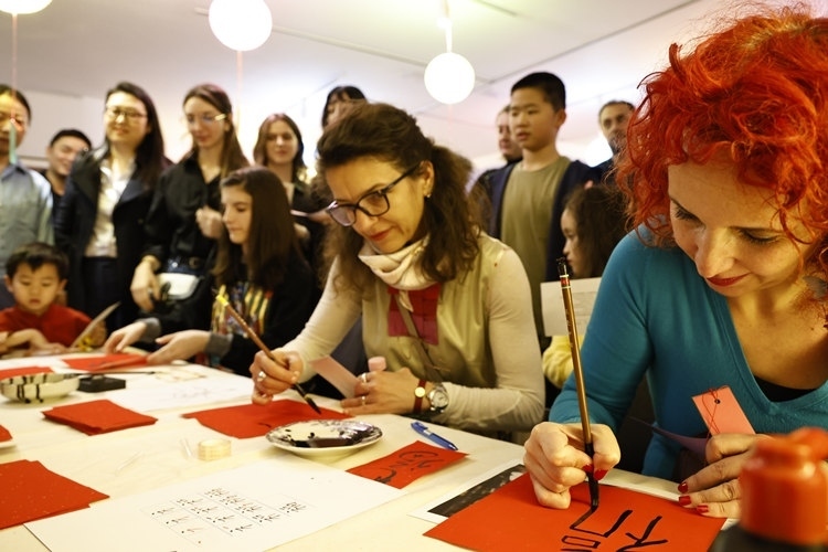 羅馬尼亞觀眾學(xué)習(xí)用毛筆寫“?！弊帧Ｖ袊幕行墓﹫D