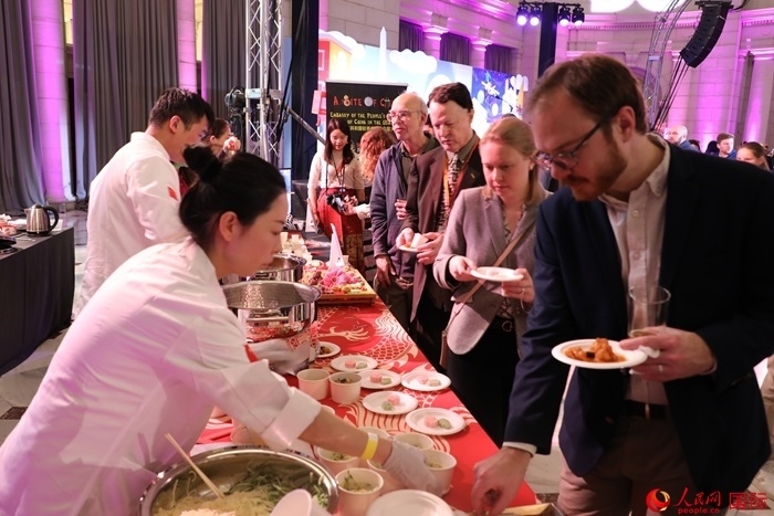 當(dāng)?shù)貢r(shí)間3月7日晚，華盛頓聯(lián)合車站廣場舉行駐美使團(tuán)“使館主廚挑戰(zhàn)賽”。圖為當(dāng)?shù)孛癖娫谥袊古_(tái)前體驗(yàn)中國美食。人民網(wǎng)記者 李志偉攝