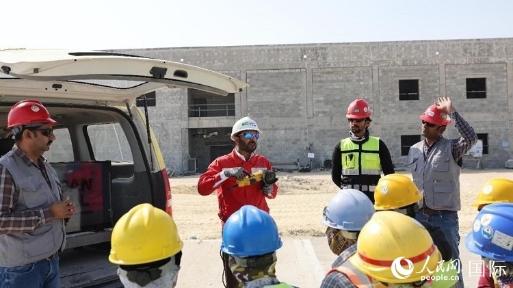 穆薩瓦爾(圖中紅衣人）現(xiàn)場(chǎng)演示工具操作規(guī)范。人民網(wǎng)記者 管克江攝