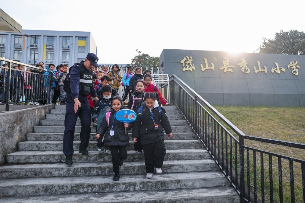 2023年12月20日，秀山派出所民警在秀山小學放學時間參與“護學崗”維持秩序，同時接獨自放學的學生去“民生小鋪”。浙江省舟山市岱山縣公安局秀山派出所聯(lián)合鄉(xiāng)鎮(zhèn)、社區(qū)成立“民生小鋪”，為當?shù)鼐用?、外來務工人員及其子女等服務，協(xié)助解決外來務工人員在工作、生活等方面的矛盾和問題，助力鄉(xiāng)鎮(zhèn)基層治理。新華社記者 徐昱 攝