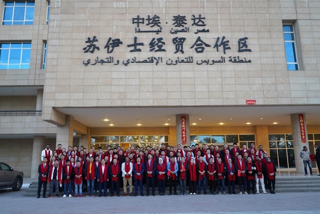 2024年2月11日，在位于埃及蘇伊士省的中?！ぬ┻_(dá)蘇伊士經(jīng)貿(mào)合作區(qū)，中埃員工在合作區(qū)辦公大樓前合影拜年。新華社發(fā)（泰達(dá)合作區(qū)供圖）