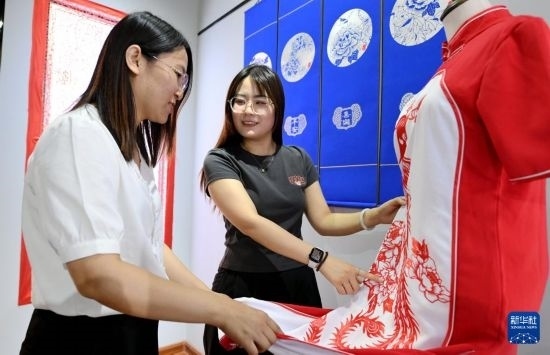 5月31日，在衡水市阜城縣一家剪紙工作室，游客在觀賞帶有剪紙?jiān)氐钠炫邸? width=