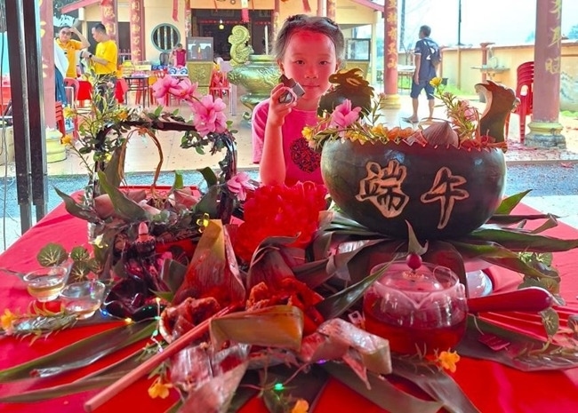 小朋友展示學(xué)裹粽子的成品照。組委會供圖