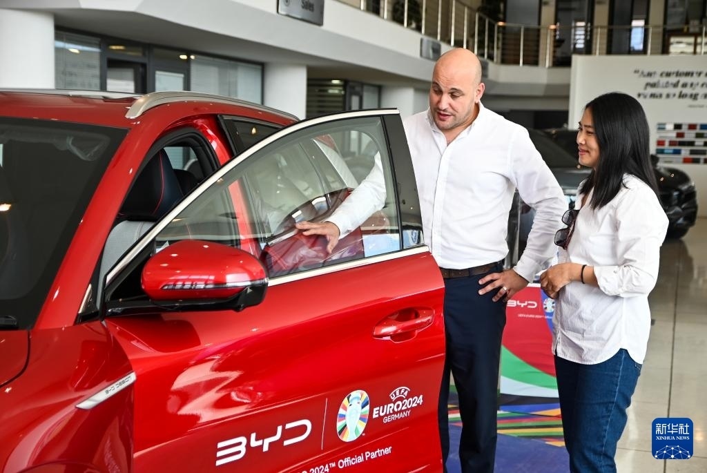 2024年5月29日，在馬耳他比爾基卡拉，馬耳他哈桑-扎米特汽車公司首席執(zhí)行官德古阿拉（左）介紹一輛比亞迪純電動(dòng)汽車。新華社發(fā)（喬納森·博格 攝）