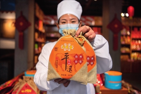 在位于山西省晉中市平遙縣的平遙古城南大街的一家平遙牛肉店內，工作人員展示一款牛肉產(chǎn)品（資料照片）楊晨光攝 / 本刊