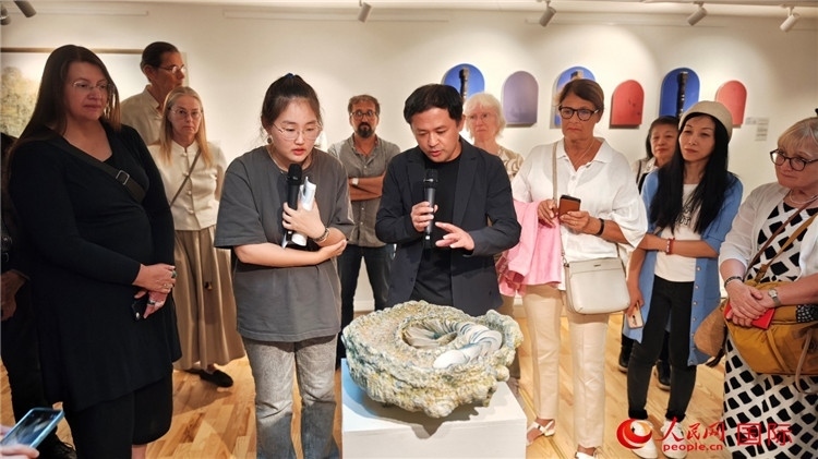 參展人、景德鎮(zhèn)陶瓷大學(xué)設(shè)計(jì)藝術(shù)學(xué)院副院長(zhǎng)余劍峰（中）向來(lái)賓介紹參展作品。人民網(wǎng)記者 殷淼攝