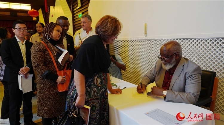 譚哲理在活動(dòng)現(xiàn)場(chǎng)簽名贈(zèng)書(shū)。人民網(wǎng) 劉暢攝