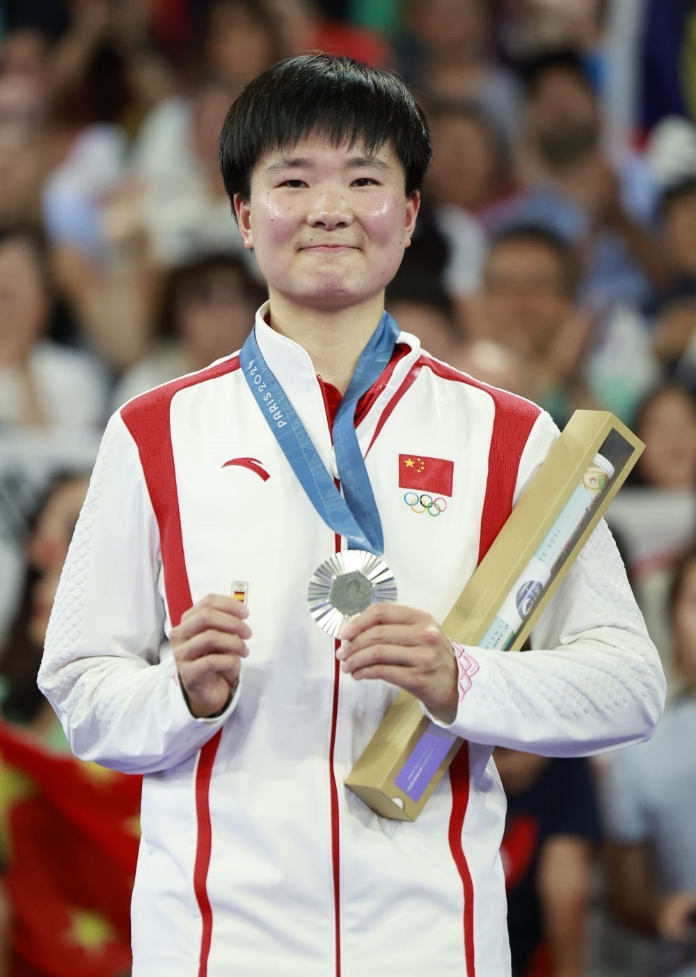 巴黎奧運會羽毛球女子單打亞軍、中國選手何冰嬌在頒獎儀式上一手握著銀牌，一手握著西班牙奧委會徽章（2024年8月5日攝）。新華社記者 任正來 攝