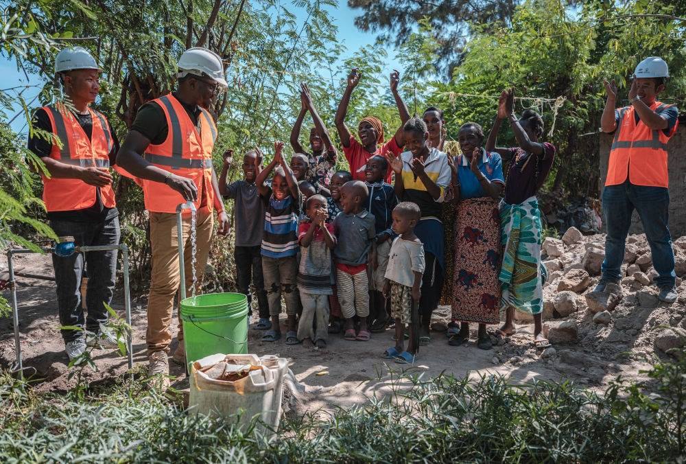 2023年6月13日，在坦桑尼亞姆萬扎省米松圭，工作人員接通水管后贏得當(dāng)?shù)鼐用窆恼茪g呼。新華社記者 王冠森 攝