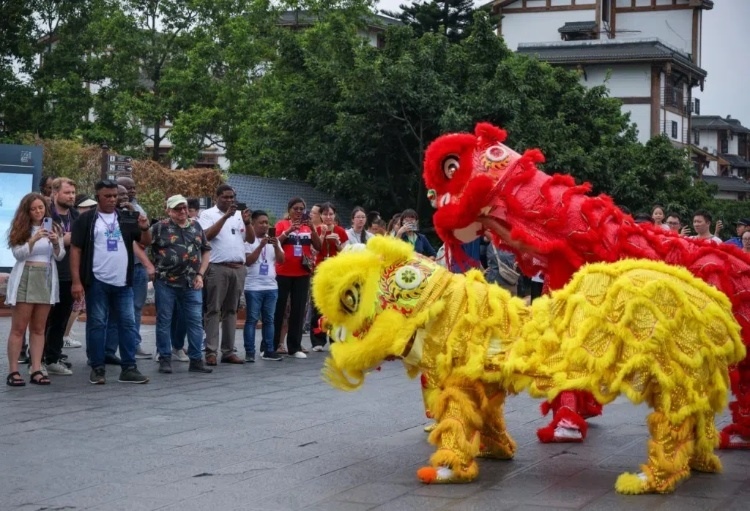 2024“一帶一路”媒體合作論壇聯(lián)合采訪調(diào)研行成員在樂山蘇稽古鎮(zhèn)觀看非遺舞獅表演。本報(bào)記者 伊霄攝