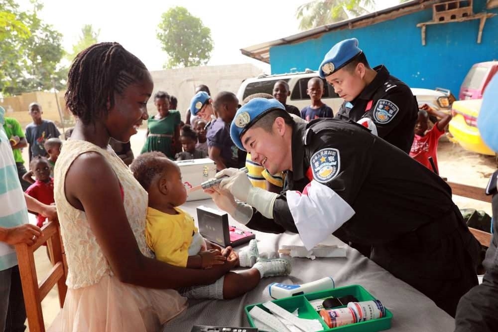 2017年12月28日，在利比里亞蒙羅維亞，中國維和警察防暴隊醫(yī)療人員為兒童做口腔檢查。