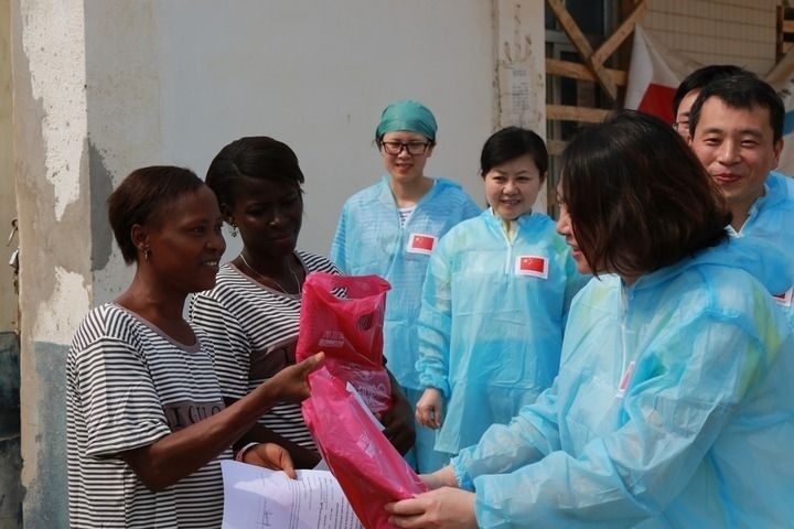 2015年4月4日，在位于塞拉利昂首都弗里敦市郊的中塞友好醫(yī)院埃博拉診療中心，中國(guó)第四批援塞醫(yī)療隊(duì)副隊(duì)長(zhǎng)邵蔚（右前）向被治愈的埃博拉出血熱患者贈(zèng)送禮物。新華社發(fā)（祖榮強(qiáng) 攝）