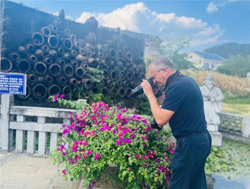 遠(yuǎn)處黔北民居錯落有致，近處一只黑色的蝴蝶穿梭于粉紫色三角梅花叢間隙，與俄羅斯“大歐亞”總編輯弗拉基米爾·別列日內(nèi)赫的鏡頭玩起了捉迷藏，“你追我逃，不亦樂乎”。（張亞欣攝）