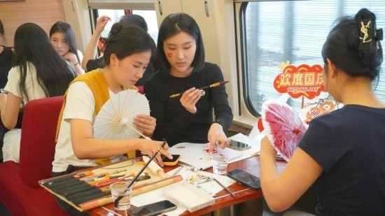 10月1日，旅客們在G1634次列車上給油紙傘作畫。新華社記者周義 攝