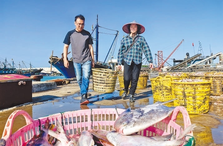 許小斌（左）和漁民一起搬運海鮮。本報記者 付 文攝