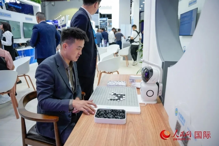 觀眾在中國移動國際有限公司展臺體驗智慧圍棋機器人。人民網(wǎng) 塔里克·易卜拉欣攝
