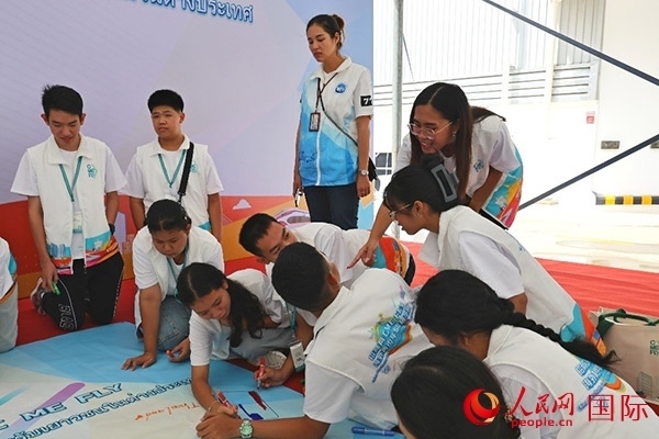 泰國學生在開營儀式展板上繪制圖案。人民網記者 白元琪攝