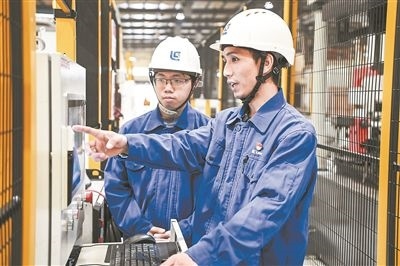 在廣西柳工機械股份有限公司生產(chǎn)車間內(nèi)，一名高級技師（右）給徒弟講解數(shù)控設(shè)備操作細(xì)節(jié)。新華社記者 曹祎銘攝