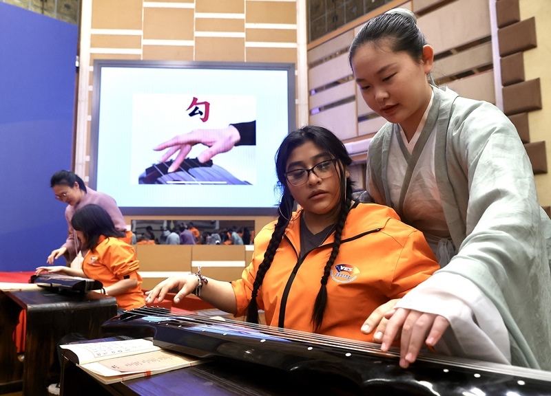 2024年3月20日，美國(guó)華盛頓州中學(xué)生代表團(tuán)北京大學(xué)交流活動(dòng)在北京大學(xué)英杰交流中心舉行。圖為來自華盛頓州的中學(xué)生體驗(yàn)古琴。