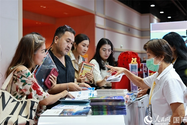 外國觀眾在中國展臺仔細閱讀赴華旅游介紹，向工作人員咨詢關(guān)于中國美食和景點的詳細信息。人民網(wǎng)記者 白元琪攝