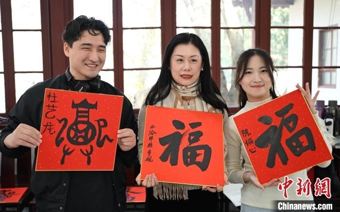 1月20日，外籍留學(xué)生和西泠印社社員李硯(中)展示各自創(chuàng)作的福貼。當(dāng)日，來自巴西、馬來西亞、加納、哈薩克斯坦的外籍留學(xué)生在浙江杭州西泠印社體驗(yàn)福貼、春聯(lián)和篆刻，感受古老的中國傳統(tǒng)文化。中新社記者 王剛 攝