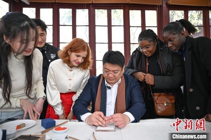1月20日，篆刻家王臻向外籍留學(xué)生展示篆刻印章。當(dāng)日，來自巴西、馬來西亞、加納、哈薩克斯坦的外籍留學(xué)生在浙江杭州西泠印社體驗(yàn)福貼、春聯(lián)和篆刻，感受古老的中國傳統(tǒng)文化。中新社記者 王剛 攝